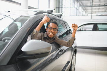 Young african american man is choosing a new vehicle in car dealership
