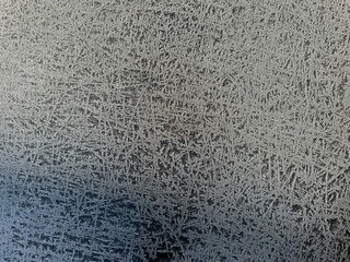 Close-up of frost patterns on a window, featuring intricate ice crystals and natural textures....
