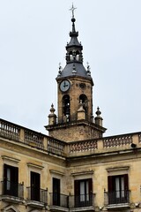Le clocher de l’église Saint-Michel de Vitoria-Gasteiz émergeant au-dessus des façades de la Place d’Espagne 