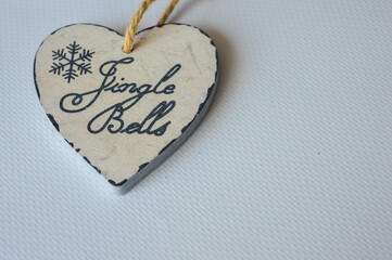 close-up of a hand holding a rustic wooden heart-shaped ornament with a snowflake design and the words 