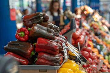 Raw juicy red bell pepper and vegetables on display at a food market. Selective focus on sweet pepper. Paprika