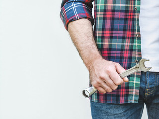Attractive man in work clothes and wrench. Labor day. Close-up, indoors. Studio shot. Front view,...