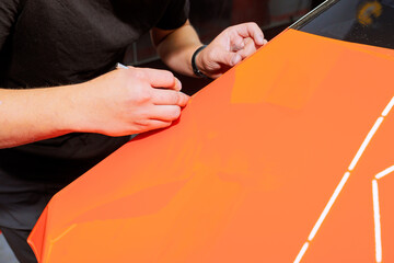 Worker is meticulously on bright orange surface, showcasing artistic skill in car service...