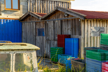 Colorful plastic fishing crates stacked outside rustic wooden shed