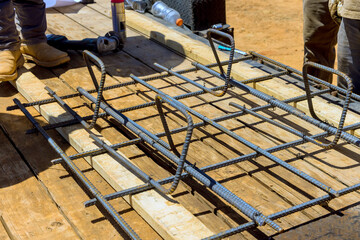 Workers prepare steel reinforcement bars on wooden platform under work day to construction task.