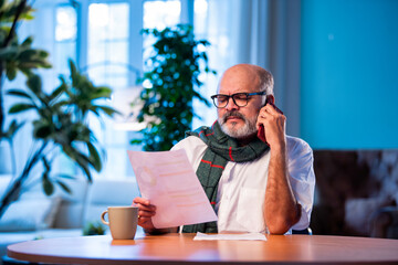 Elderly Indian man calls CA to talk about tax report while sitting at home table