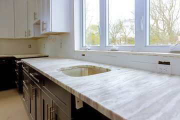 Kitchen cabinetry renovation featuring marble countertop bright windows, showcasing an unfinished but elegant design.