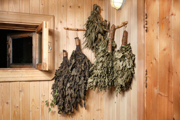 Dry brooms in the bath are hanging on the wall. 