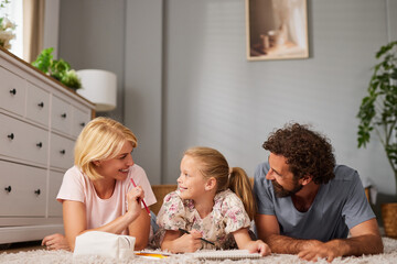A family of three engages in a creative activity on the floor of their living room, sharing smiles...