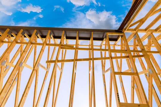 Wooden beams frames are being assembled under clear sky as construction progresses on building.