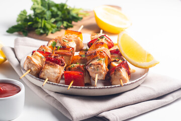 Delicious grilled chicken skewers with capsicum, lemon, salad and ketchup on a plate over the table. Chicken kebab. Healthy food concept.