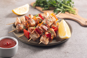 Delicious grilled chicken skewers with capsicum, lemon, salad and ketchup on a plate over the table. Chicken kebab. Healthy food concept.