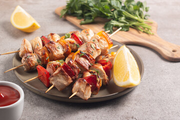 Delicious grilled chicken skewers with capsicum, lemon, salad and ketchup on a plate over the table. Chicken kebab. Healthy food concept.