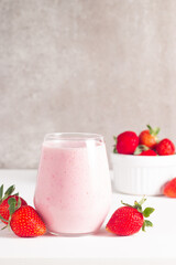 Glass of fresh strawberry milkshake, smoothie and fresh strawberries on white and wooden background. Healthy food and drink concept.