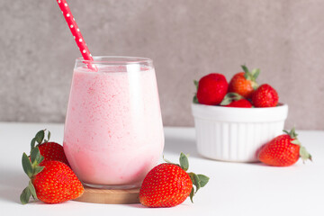Glass of fresh strawberry milkshake, smoothie and fresh strawberries on white and wooden background. Healthy food and drink concept.