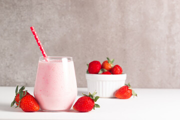 Glass of fresh strawberry milkshake, smoothie and fresh strawberries on white and wooden background. Healthy food and drink concept.