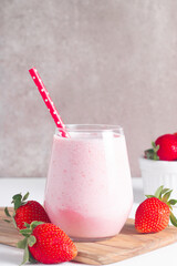 Glass of fresh strawberry milkshake, smoothie and fresh strawberries on white and wooden background. Healthy food and drink concept.