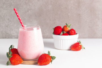 Glass of fresh strawberry milkshake, smoothie and fresh strawberries on white and wooden background. Healthy food and drink concept.
