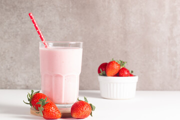 Glass of fresh strawberry milkshake, smoothie and fresh strawberries on white and wooden background. Healthy food and drink concept.