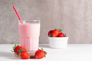 Glass of fresh strawberry milkshake, smoothie and fresh strawberries on white and wooden background. Healthy food and drink concept.