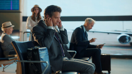 Businessman wearing wireless earbuds in airport lounge
