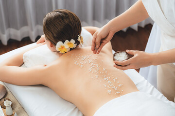 Woman customer having exfoliation treatment in luxury spa salon with warmth candle light ambient....