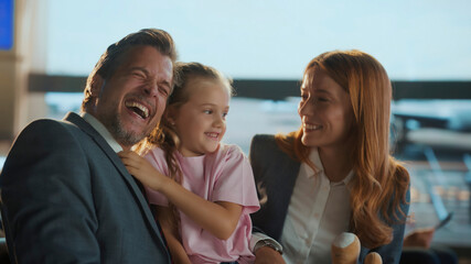 Happy family laughing together in airport business lounge while waiting for flight