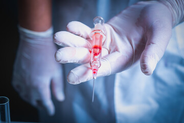 Scientist holding a syringe with a blood sample in the lab. Vaccine development or medical trials.