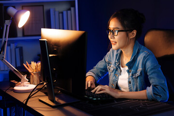 Smiling young beautiful asian creative officer looking on pc in sales target online, earning job's...