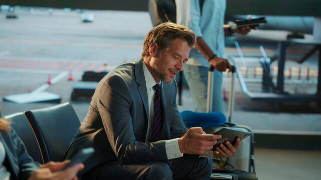 Businessman using tablet and waiting for flight in airport lounge