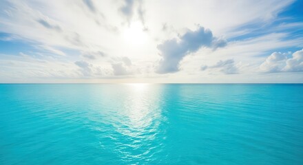 Obraz premium Bright sunlight shines over a calm turquoise ocean, reflecting on the water's surface with scattered clouds in the blue sky above.