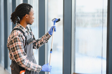 African American Skilled technician cleaning large office windows