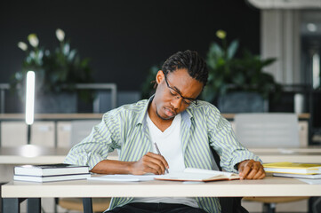 Focused university student studying and taking notes in library