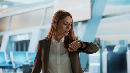 Businesswoman checking time on smartwatch at airport terminal