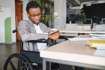 Focused african american student in wheelchair studying in modern university library