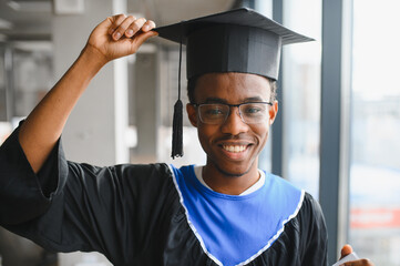 Happy african american graduate student holding graduation cap and smiling at university