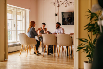 Colleagues discussing project ideas and strategies at office desk while collaborating in business meeting