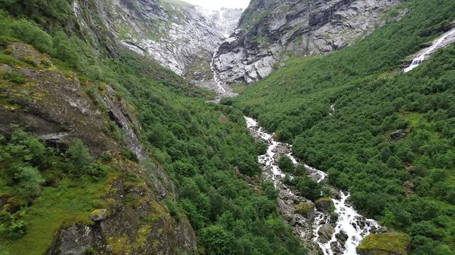 River Flowing Through Briksdalen Valley Under Overcast Sky
