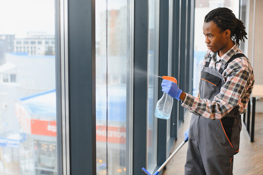 African American Professional cleaning service worker washing windows in office building