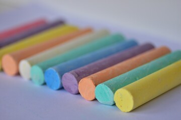 Fototapeta premium Side angle view of large pastel chalk sticks arranged in neat rows. Artistic texture and vibrant colors represent creative expression, school supplies, and children drawing tools.