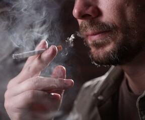 Man smoking cigarette on blurred background, closeup