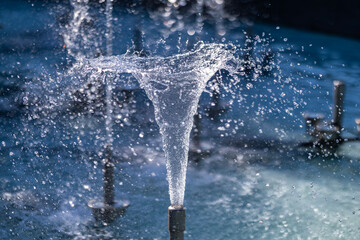 A close-up of a fountain jet forming a swirling cone of water, with dynamic splashes and droplets,...