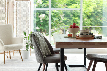 Wooden table, chairs, armchair and decor in dining room. Interior design