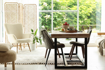 Wooden table, chairs, armchair and decor in dining room. Interior design