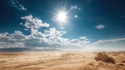 A bright sun shines over a vast desert, illuminating golden sand dunes. Wispy clouds drift across a clear blue sky, while gentle winds stir up the loose sand, creating a serene yet dynamic atmosphere.
