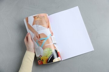 Woman reading magazine at light grey table, top view. Mockup for design