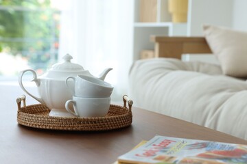 Teapot, cups and magazines on coffee table in dining room
