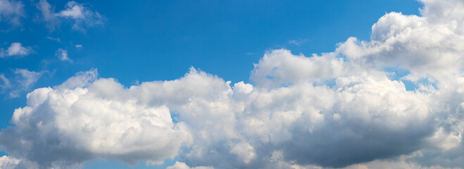 Bright blue sky with large fluffy white clouds, creating a panoramic and serene sky landscape © Iryna
