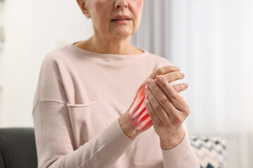 Arthritis. Senior woman suffering from pain in hand indoors, closeup. Illustration of joint inflammation