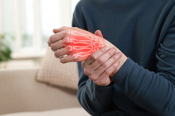 Arthritis. Man suffering from pain in hand indoors, closeup. Illustration of joint inflammation